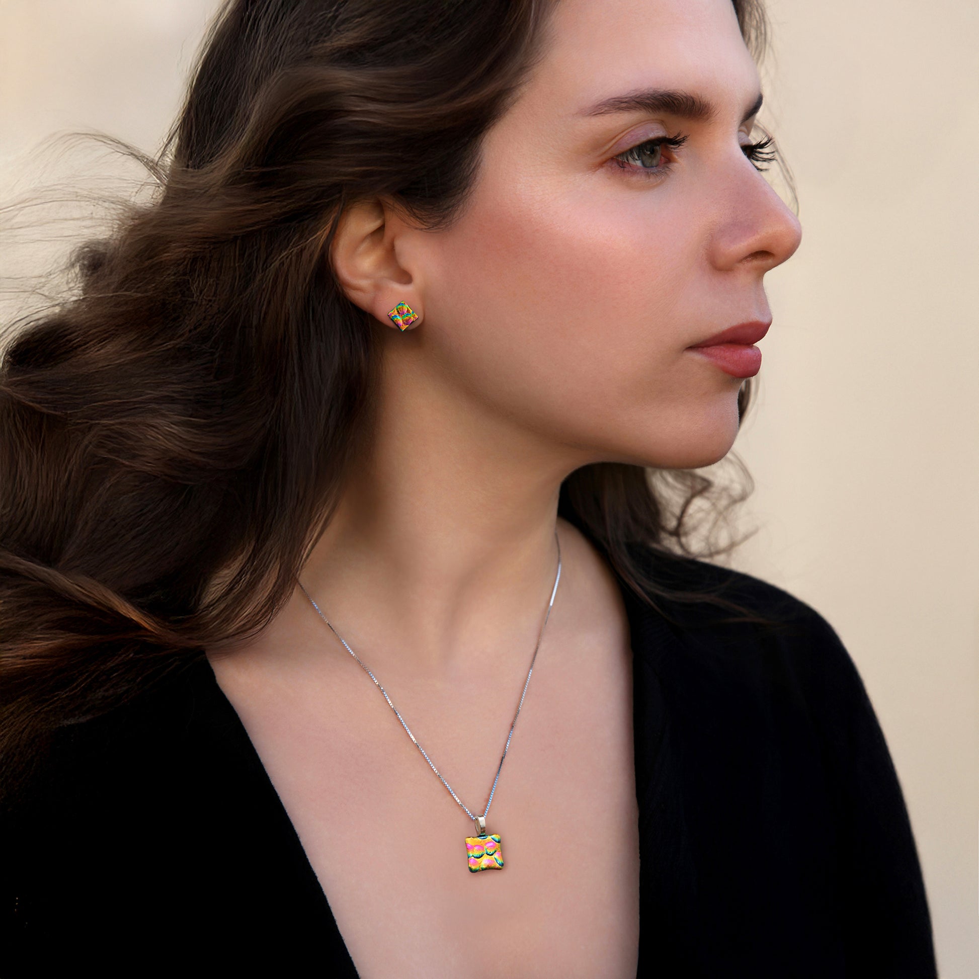 Woman wearing a necklace with a colorful pendant against a neutral background