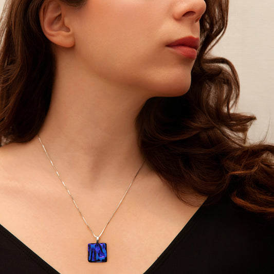 Close-up of a woman wearing a necklace with a blue ripple pendant.