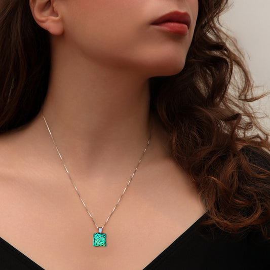 A close up of a woman wearing a green crinkle dichroic glass square pendant on a silver chain. Handmade design from the Astra collection.