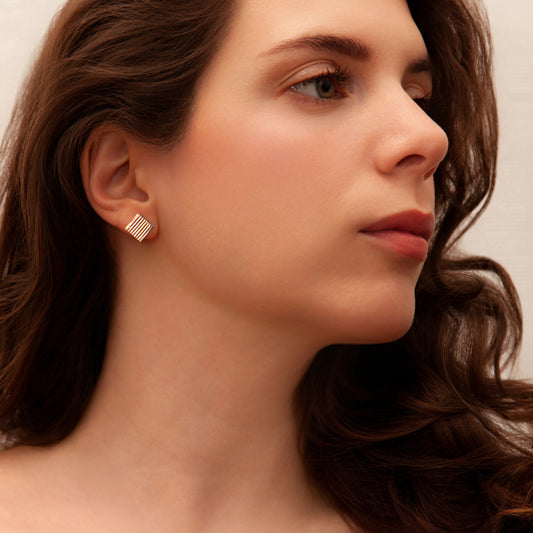 Handcrafted gold stripe dichroic glass stud earrings worn by model, glowing with warm amber and coppery tones.