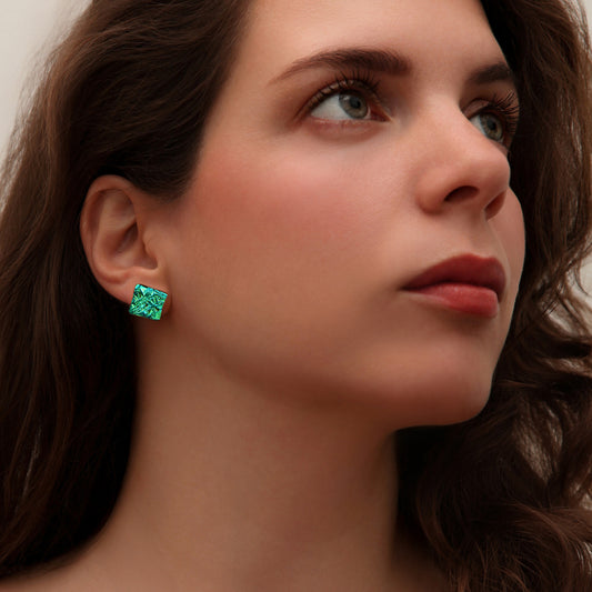 Close-up of model wearing green crinkle dichroic glass square stud earrings from Madiha Zaidi’s Astra collection.