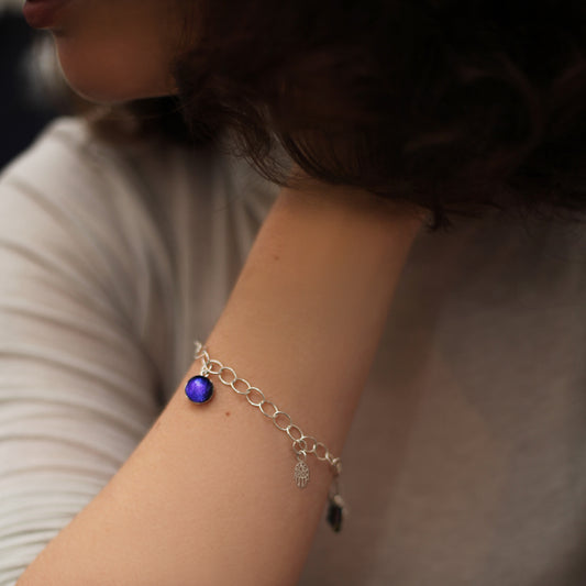 Close-up of a person's arm wearing a silver bracelet with a purple gemstone.