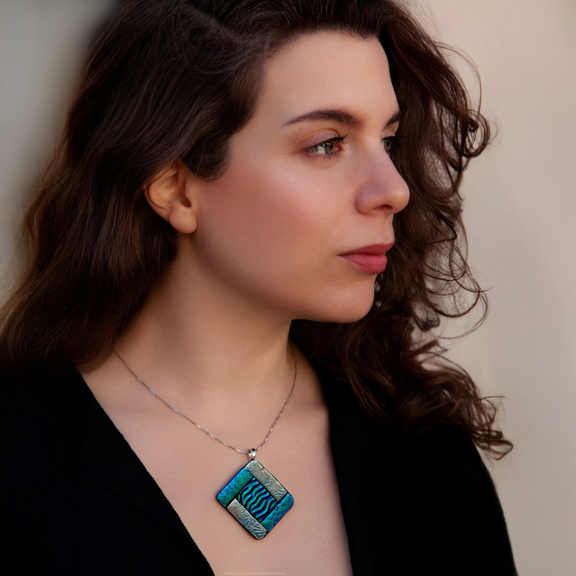 Model wearing Elementa Earth necklace by Invoke London with green fused glass pendant and silver, symbolising growth and balance.