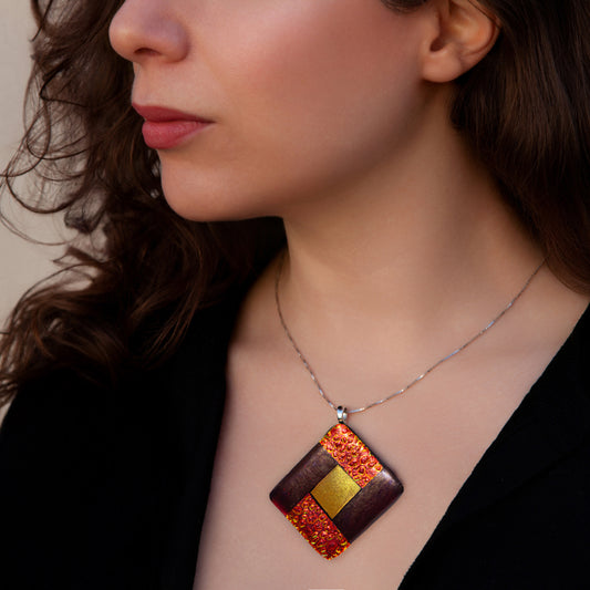 Close-up of model wearing Elementa Fire necklace by Invoke London with bold red-gold fused glass pendant symbolising energy and courage.