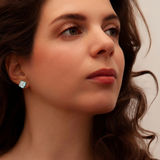Close-up of a woman wearing silver cube stud earrings