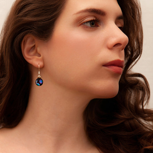 Close-up of a woman wearing a green hexagon glass drop earrings