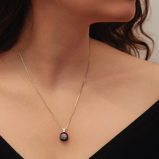 Close-up of pink rainbow dichroic glass pendant on sterling silver chain from the Orb collection by Invoke London.