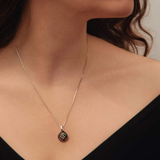 Close-up of round black dichroic glass pendant with red square shimmer on sterling silver chain from the Orb collection by Invoke London.