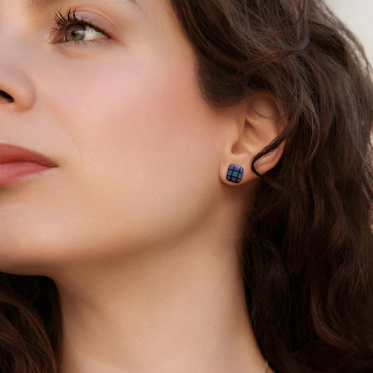 Close-up of a woman wearing a blue square pattern stud earring.