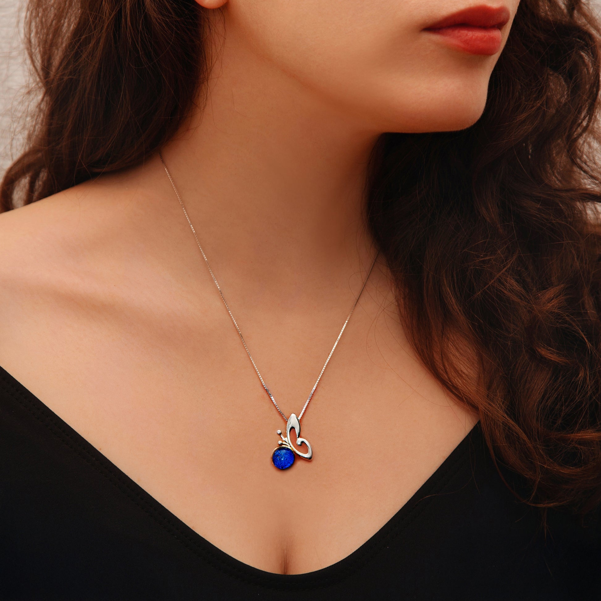Close-up of blue dichroic glass butterfly pendant, shimmering with colour-shift sparkle.