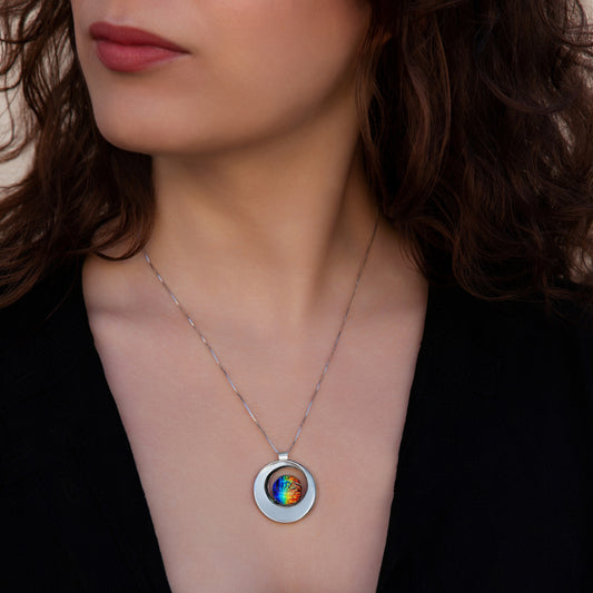 Close-up of a model wearing a handmade Stella necklace featuring a circular silver pendant with a vibrant rainbow dichroic glass cabochon at the centre, by Invoke London.