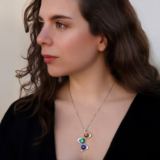 Model wearing Stella necklace with orange, green, and blue dichroic glass cabochons. Handcrafted by Invoke London.