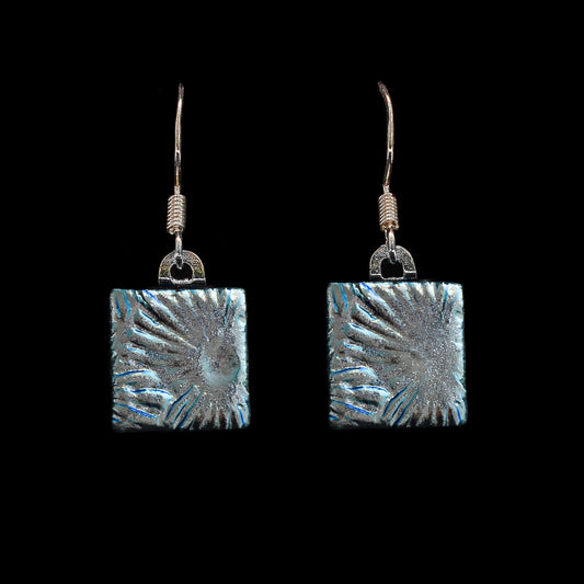 Pair of square silver florentine dichroic glass drop earrings from the Astra collection by Invoke London on black background.