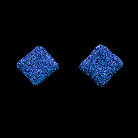 A pair of square-shaped, blue crinkle dichroic glass stud earrings against a black background.