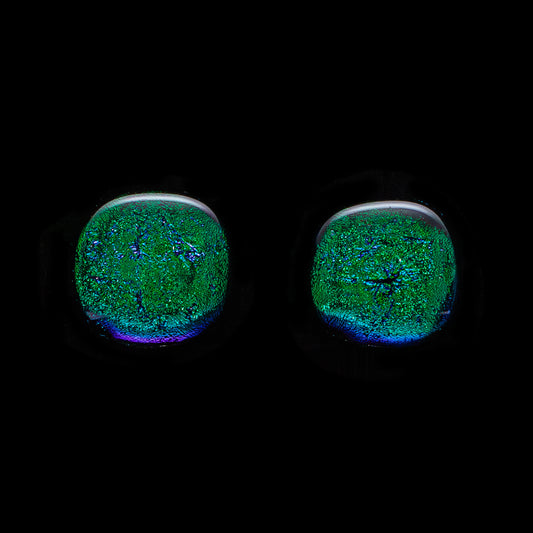 A pair of large, round, dark green dichroic glass stud earrings against a black background.