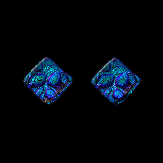 A pair of blue cube-shaped stud earrings with a geometric pattern, set against a black background.