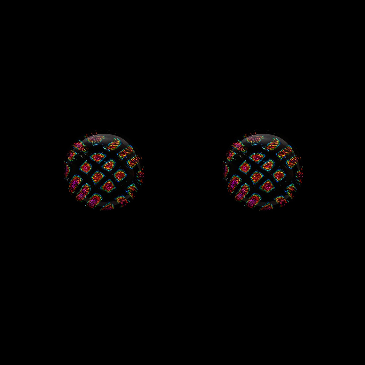 A pair of round stud earrings featuring a black and red square pattern on a dichroic glass surface.