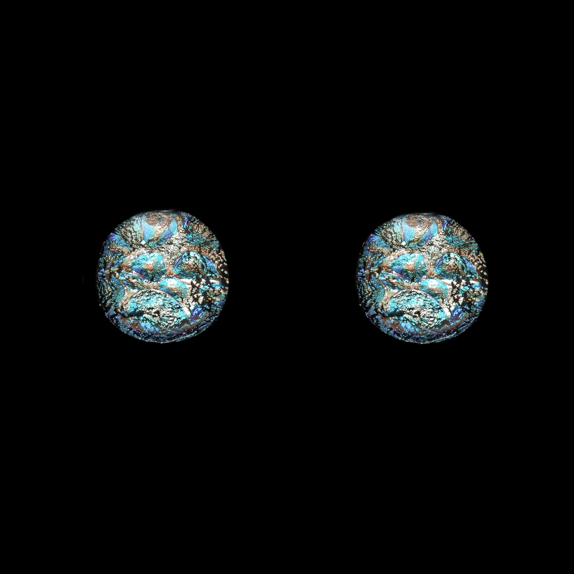 Round stud earrings in silver-toned dichroic glass with turquoise and teal highlights, handcrafted as part of the Orb Collection by Invoke London.