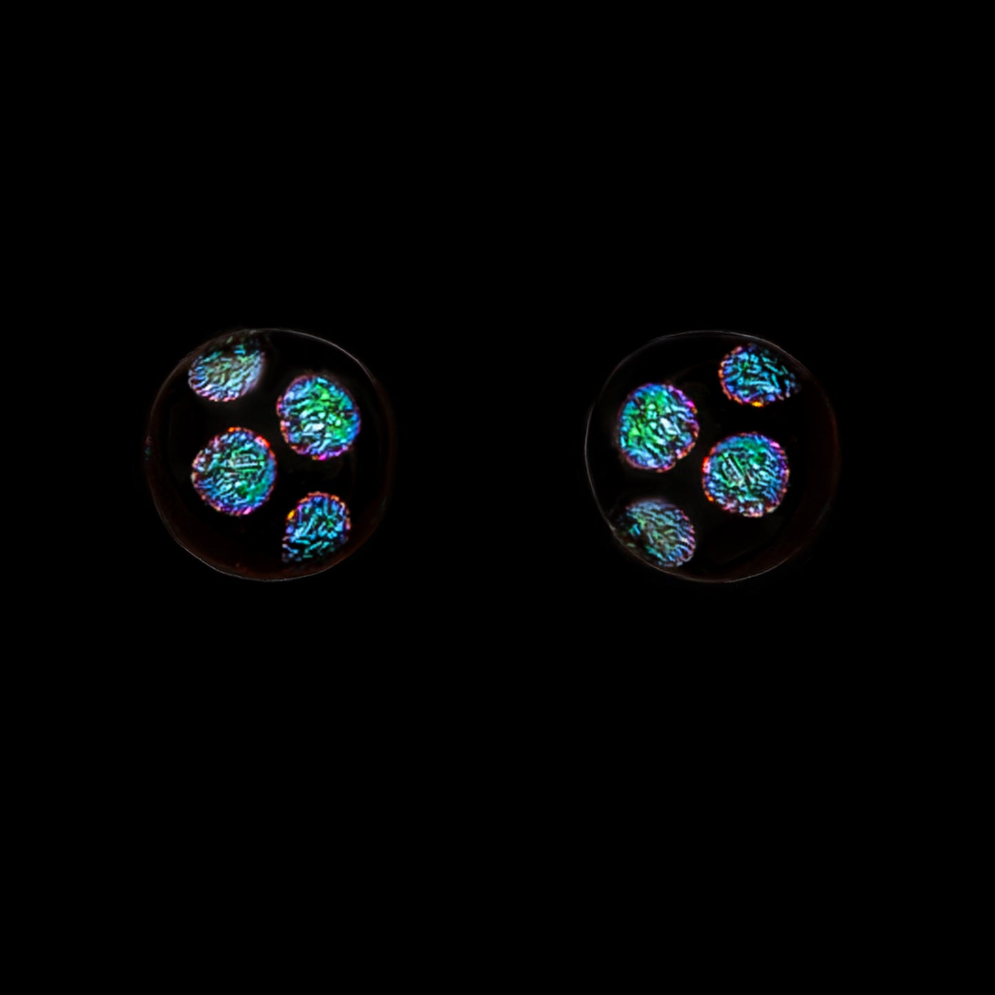 Stud earrings with green dots on a black background