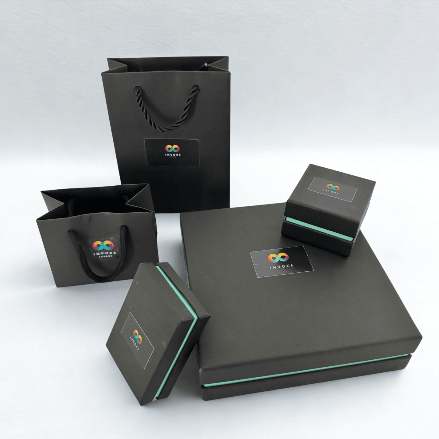 Sustainable black jewellery boxes and gift bags with Invoke London logo and teal edge detail, ideal for gifting handmade glass jewellery.
