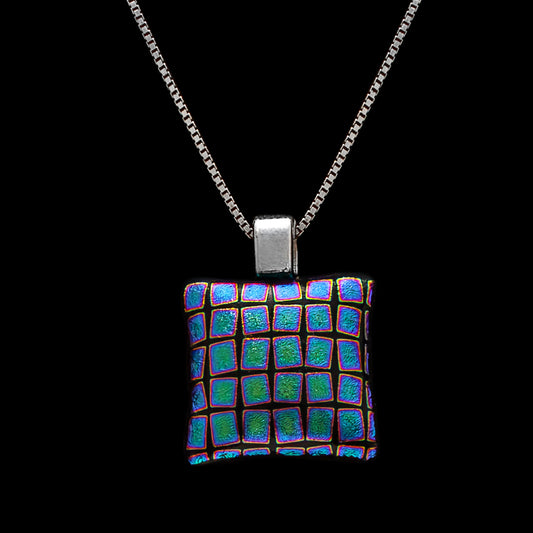 A square-shaped dichroic glass pendant necklace with black and blue squares pattern, attached to a silver chain.
