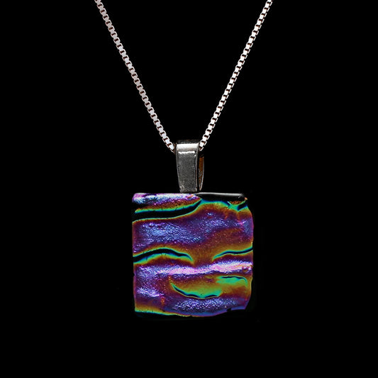 A square-shaped, multicolored dichroic glass pendant necklace with a pink ripple pattern, suspended from a silver chain.