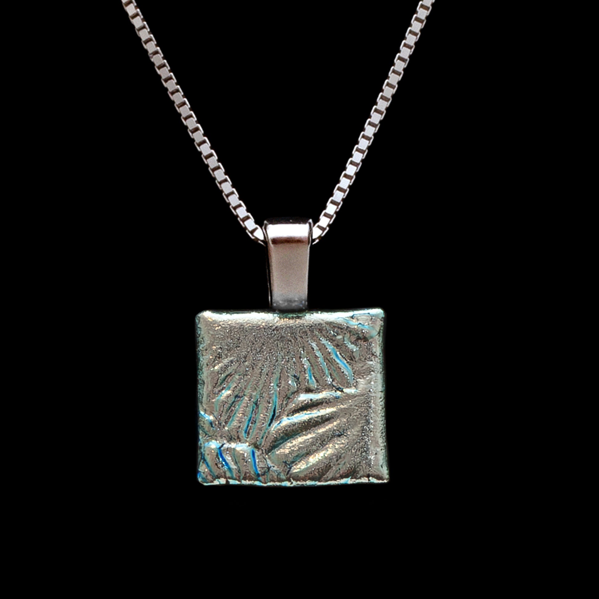 Handmade square pendant in silver dichroic glass with a radiating sunburst design, on a sterling silver chain from Invoke London's Astra collection.
