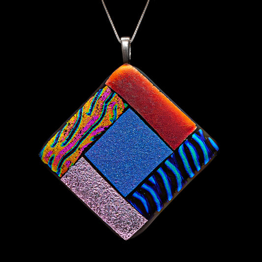 Close-up of the Elementa Combination necklace by Invoke London, showcasing a vibrant fused glass design in red, green, blue, and white to represent the four natural elements.