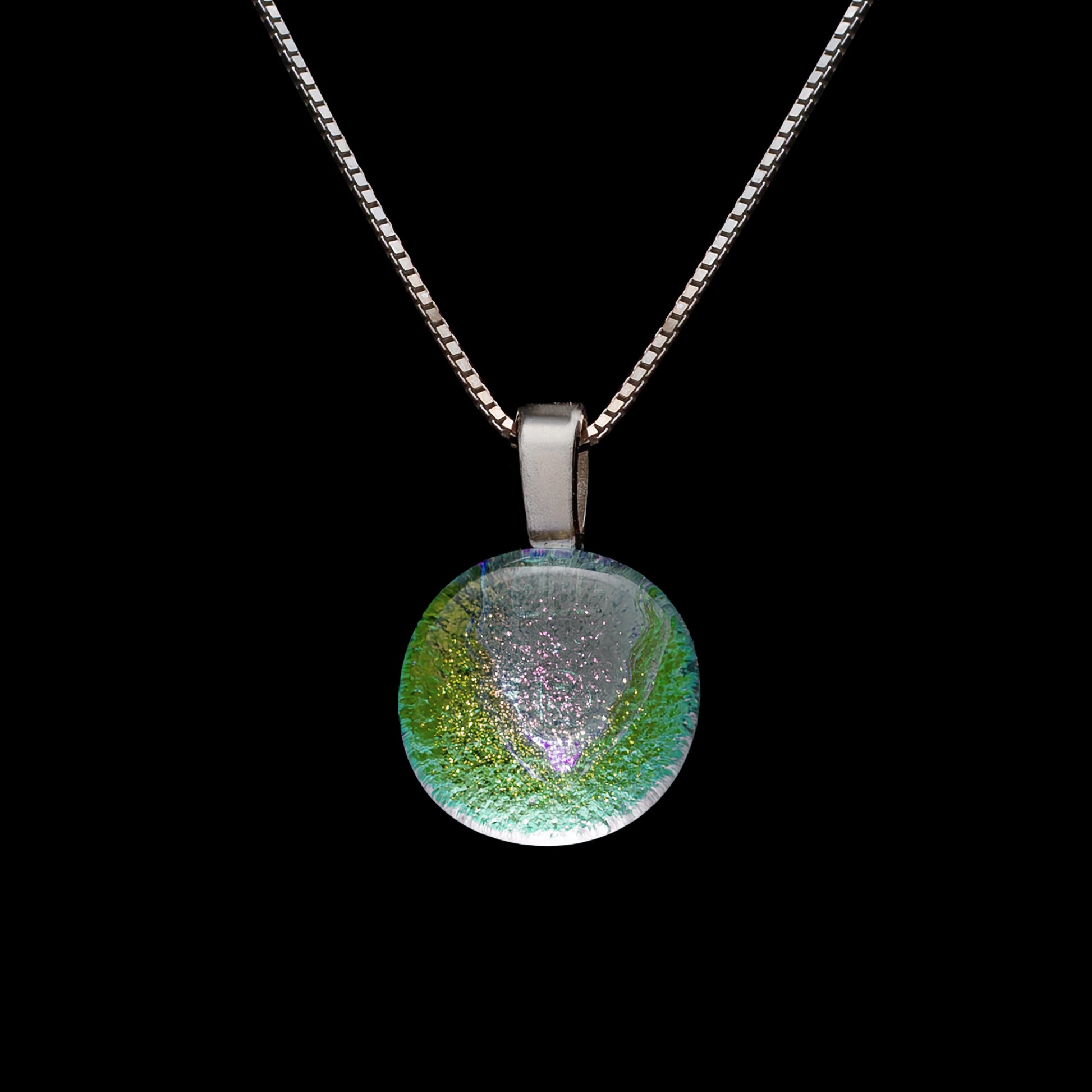 A round dichroic glass pendant necklace in clear green, with a sterling silver chain.