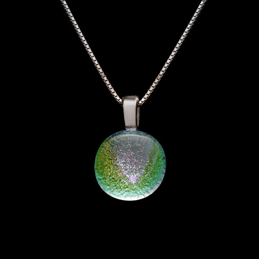 A round dichroic glass pendant necklace in clear green, with a sterling silver chain.