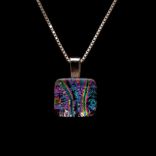 A glass artist's handmade necklace featuring a dichroic glass cube pendant with pink stripes, encased in a clear glass cap, suspended from an 18-inch sterling silver chain.