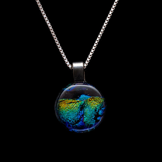 Green and gold ripple dichroic glass pendant on a sterling silver chain, handmade in London by glass artist Madiha Zaidi.