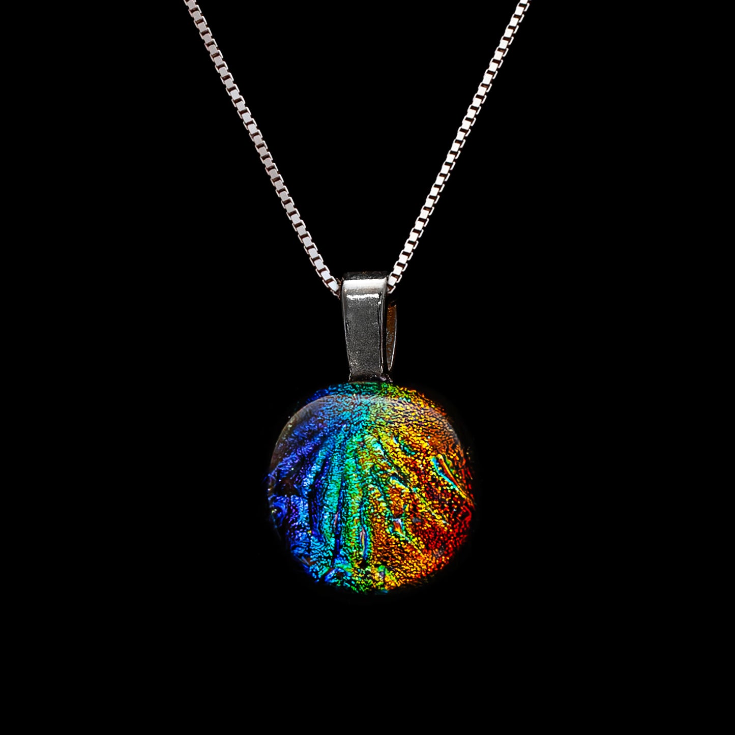 Round pendant necklace from the Orb Collection by Invoke London, featuring rainbow-toned dichroic glass with a textured Florentine finish and silver-tone bail.