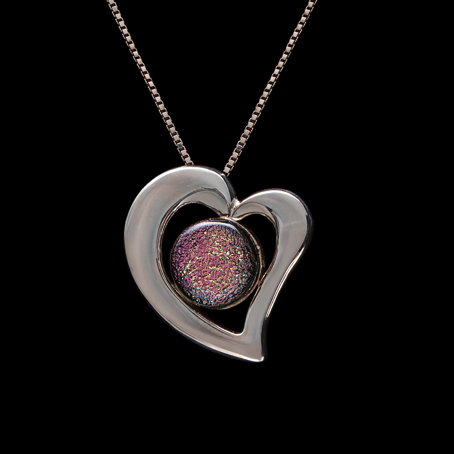 Pink dichroic glass heart necklace with silver-plated frame on a sterling silver chain, handmade in London by glass artist Madiha Zaidi.