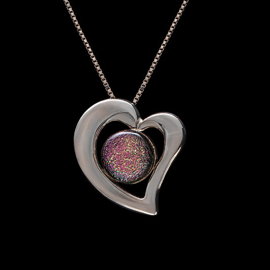 Pink dichroic glass heart necklace with silver-plated frame on a sterling silver chain, handmade in London by glass artist Madiha Zaidi.
