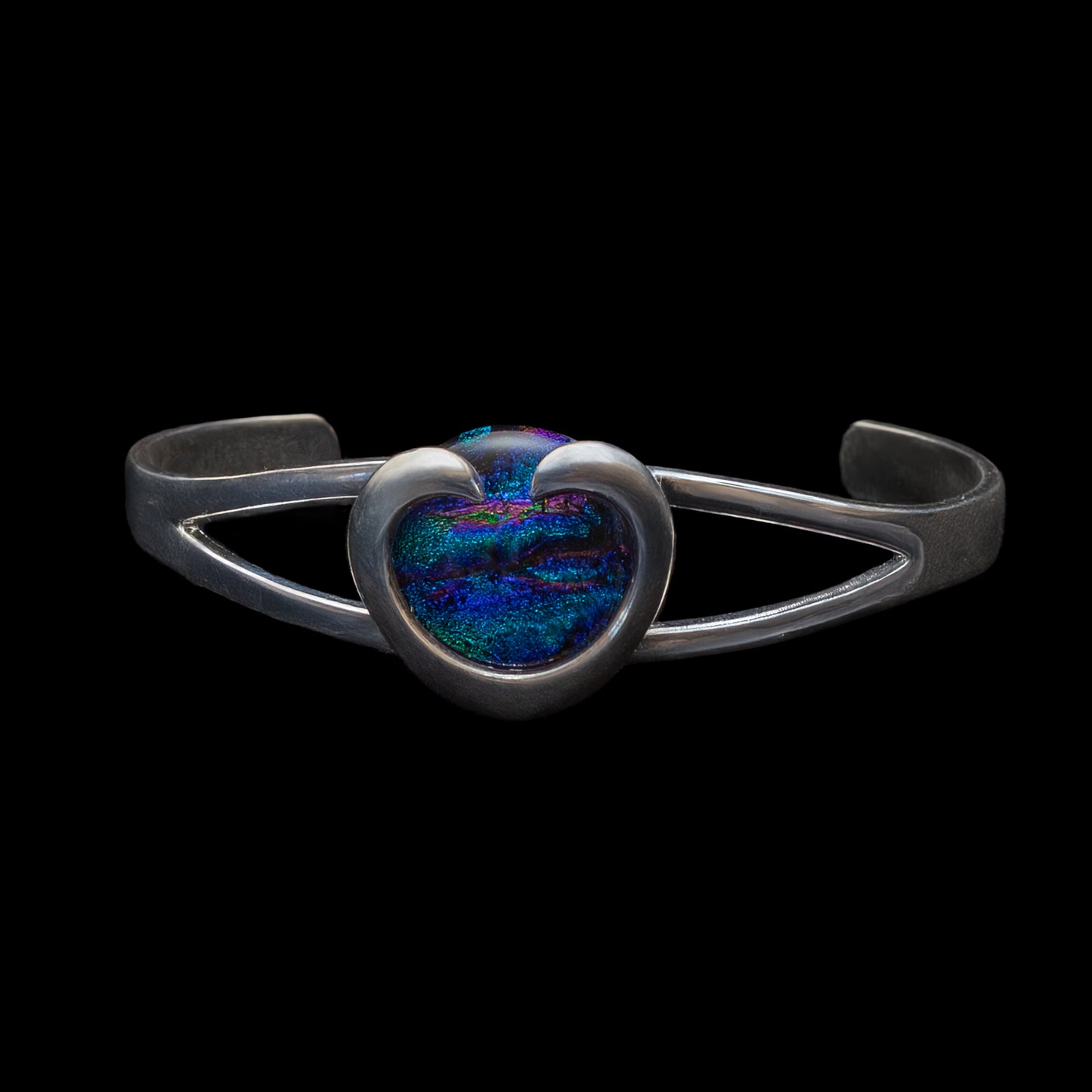 Silver bracelet with a heart-shaped, green, blue, purple stone on a black background
