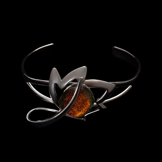Silver bracelet with a central orange dichroic glass stone on a black background
