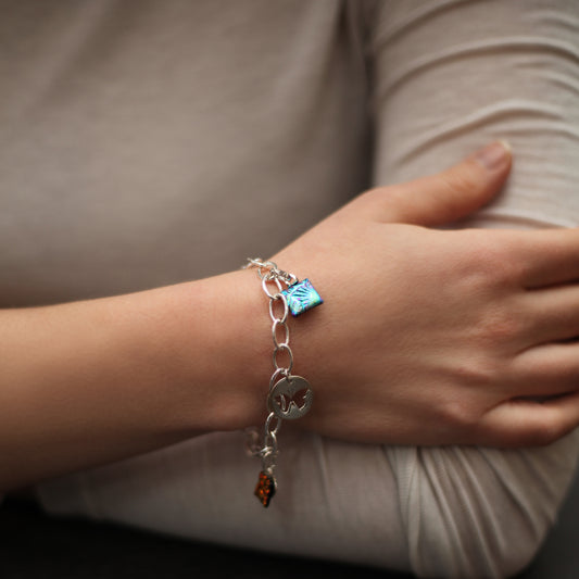 Close-up of a person's wrist wearing a bracelet with charms.
