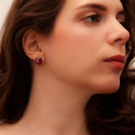 Close-up of a woman wearing a red earring with a neutral background