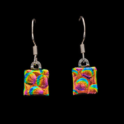 Square dichroic glass drop earrings in gold, pink, and blue with bubble texture. Handmade in London by Invoke London with sterling silver hooks.