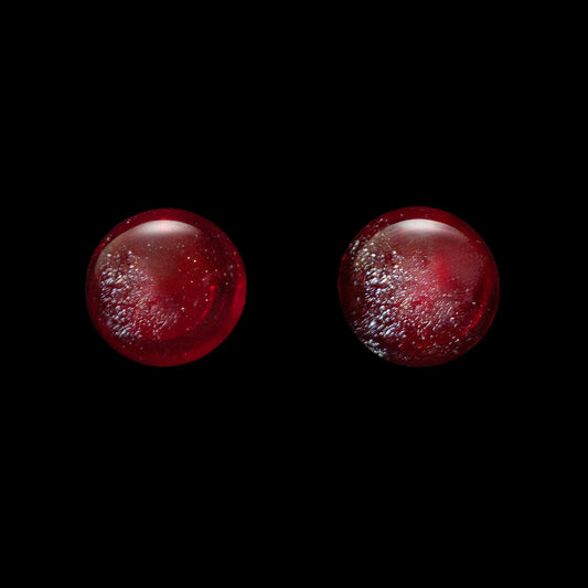Two red stud earrings on a black background