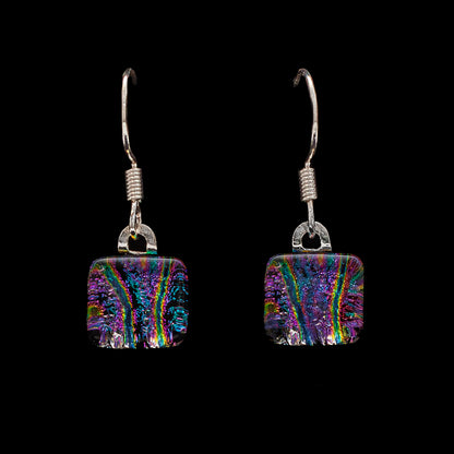A pair of pink striped dichroic glass cube drop earrings with sterling silver hooks on a black background.