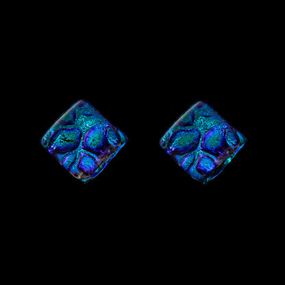 A pair of blue cube-shaped stud earrings with a geometric pattern, set against a black background.