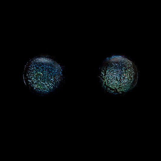 Pair of round earrings with a glittery green texture on a black background