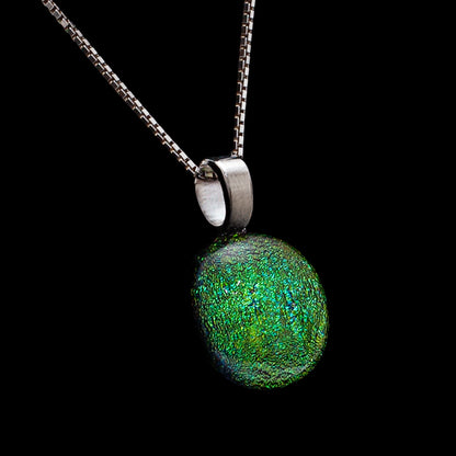 Green textured pendant on a chain against a black background