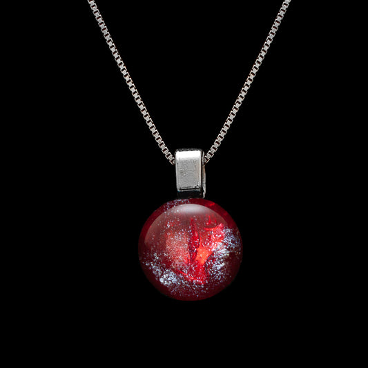 A silver necklace with a red glass gemstone pendant.