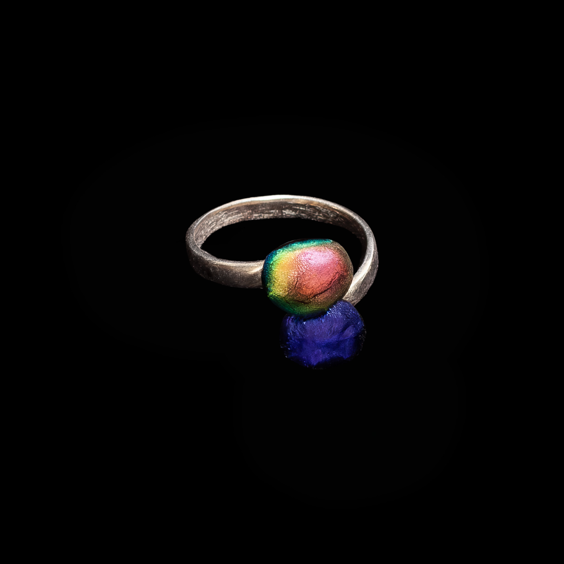 Silver ring with two gemstones in pink and purple on a black background